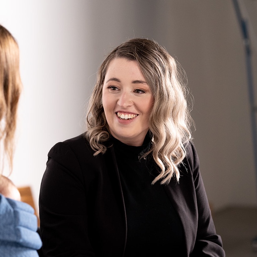 Lauren smiling while working with a client on her laptop